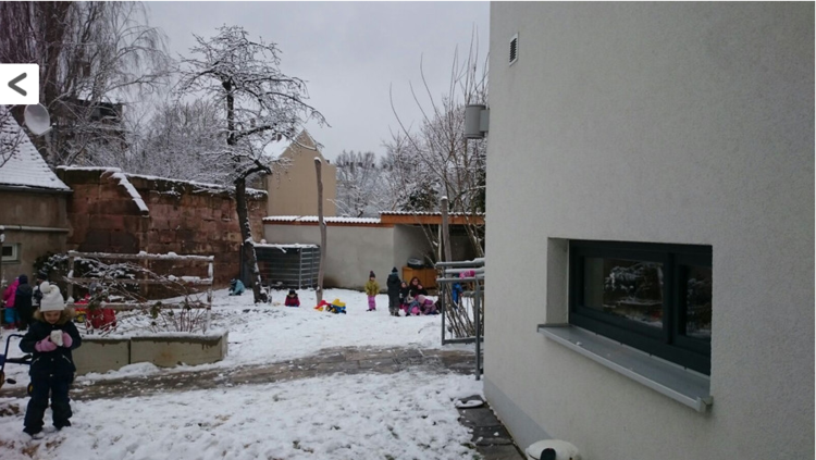 Kinder spielen draußen im Schnee. Ein Kind steht weiter vorn und hält ein Spielzeug in seinen Händen.